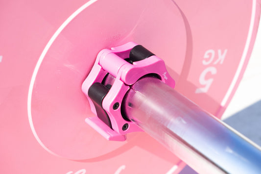 Close-up of a pink weight plate on a barbell with pink freyja adjustable collars