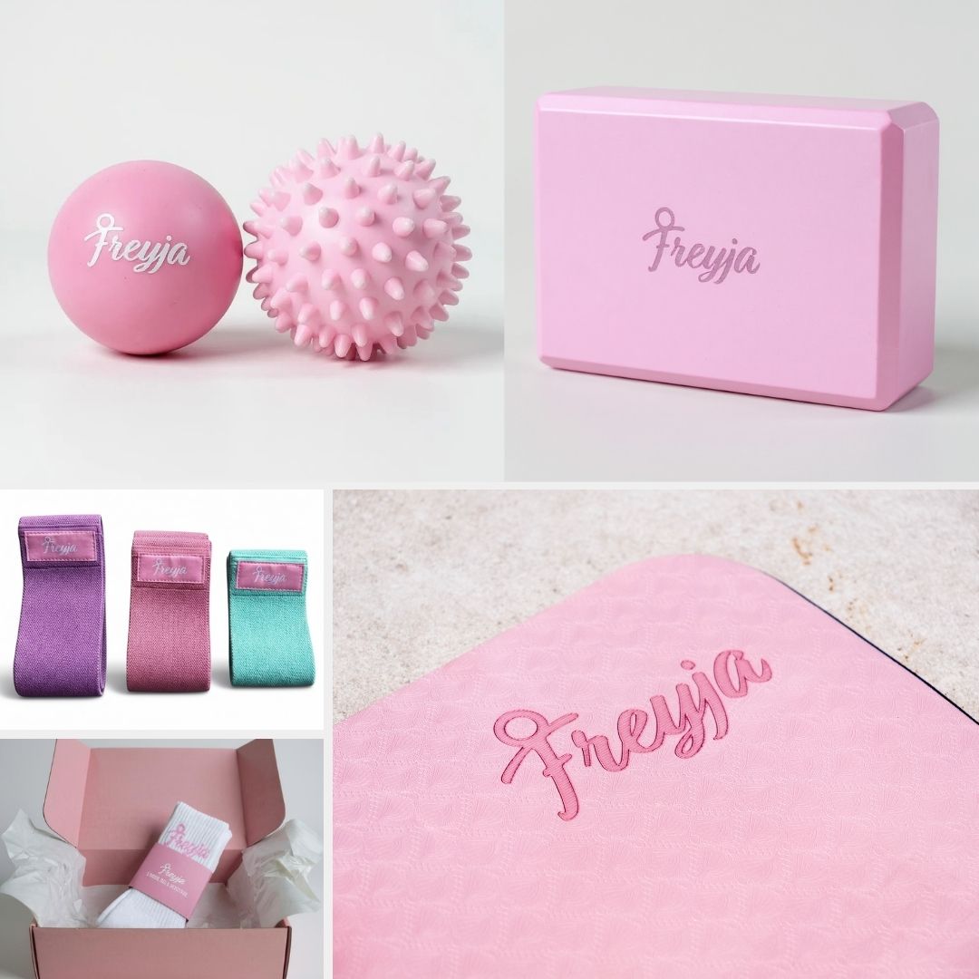Pink Freyja fitness set including massage balls, exercise bands, yoga block, and yoga mat with branded packaging.