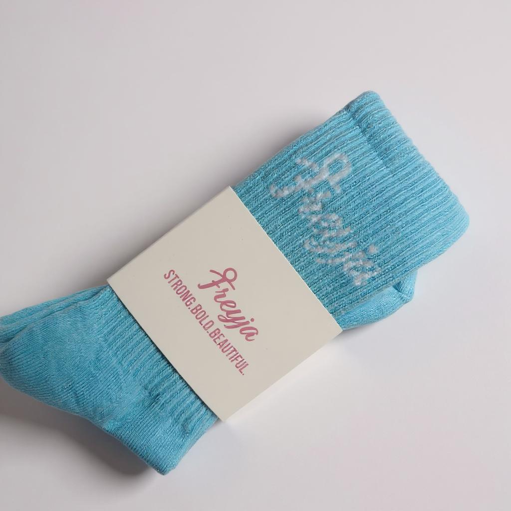 Blue Freyja socks with a white label on a grey background