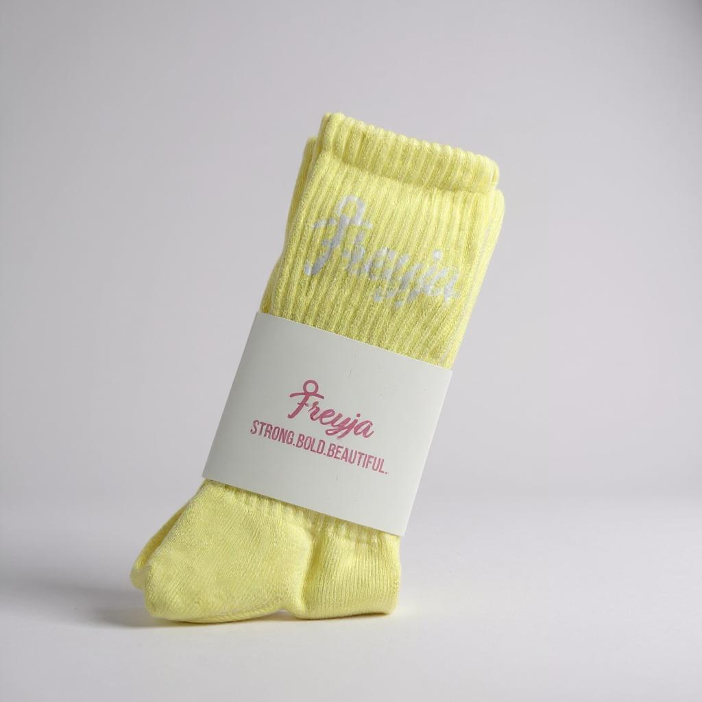 Yellow Freyja branded sock with a white label on a light grey background