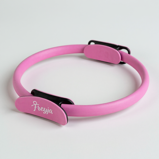 Pink freyja pilates ring with padded handles on a white background