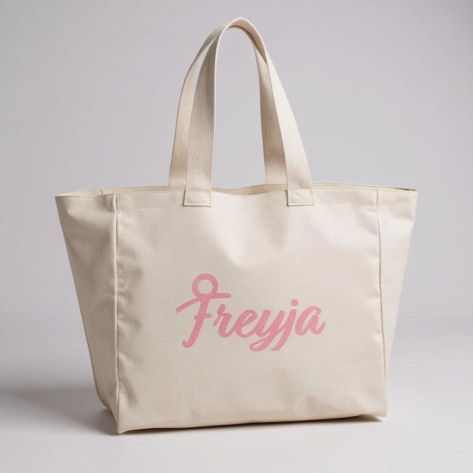 Beige Freyja tote bag with pink text 'Freyja' on a light grey background