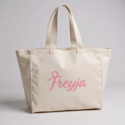 Freyja Tote Bag in cream canvas featuring pink logo design for everyday use.