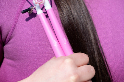 Pink Freyja Fit skipping rope held by a woman, with a purple t-shirt in the background, for fitness and cardio workouts.