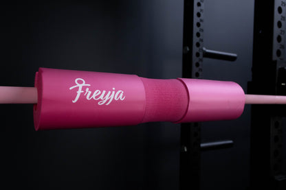 Pink freyja foam barbell on a pink barbell in a gym setting 