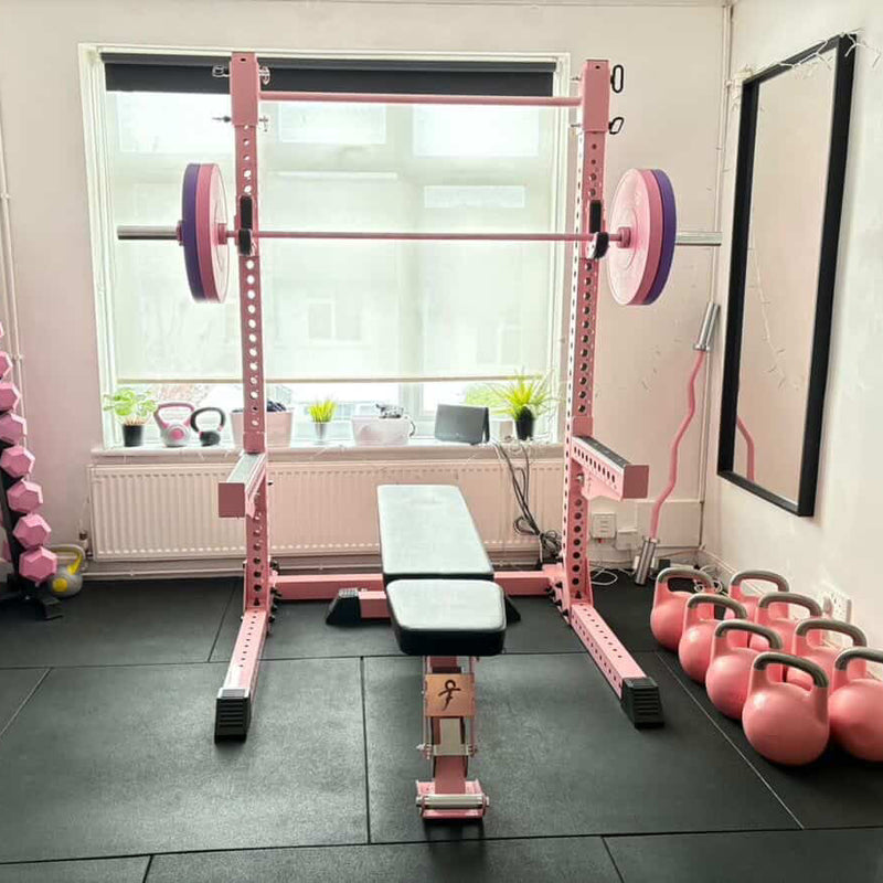 Pink weightlifting equipment in a home gym setting with weights and benches.