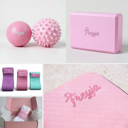 Pink Freyja fitness set including massage balls, exercise bands, yoga block, and yoga mat with branded packaging.