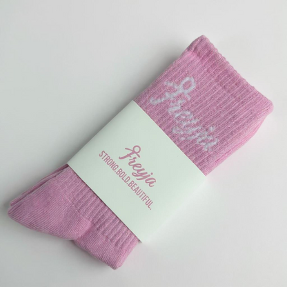 Pink Freyja socks with a white label on a light grey background