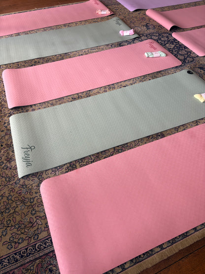 A row of freyja yoga mats in pink and green in a room 