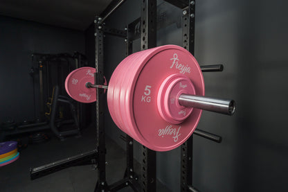 Pink Freyja Fit weight plate on a barbell rack in a gym setting