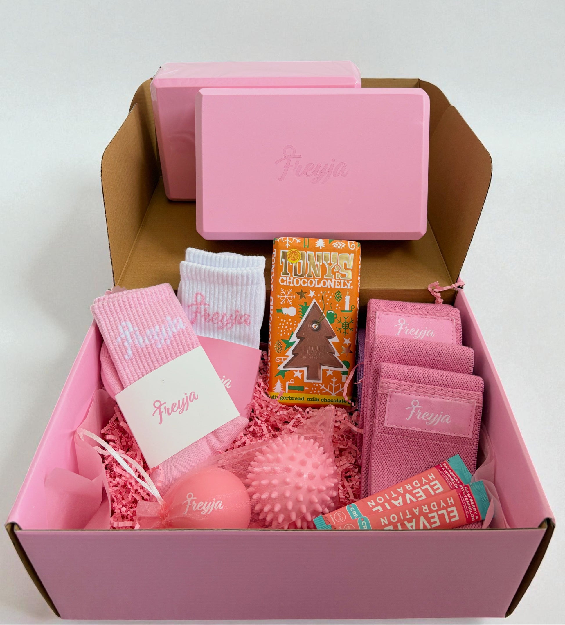 Pink edition fitness gift set including socks, workout accessories, chocolate, and yoga blocks in branded packaging