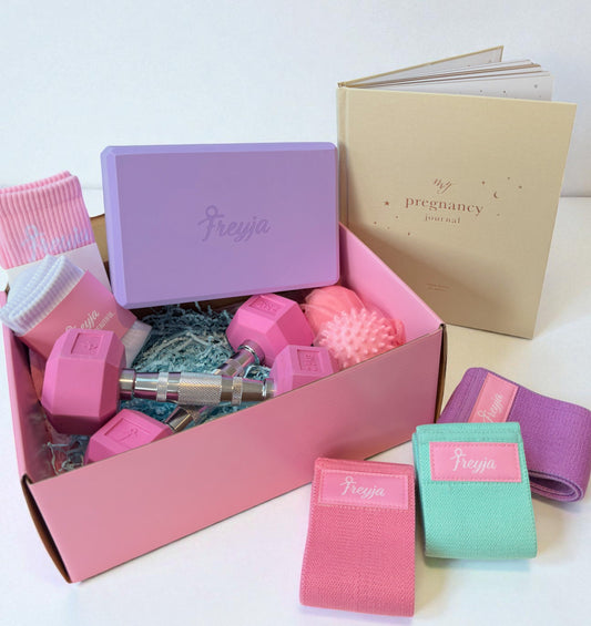 Pregnancy gift set with pink dumbbells, resistance bands, socks, massage ball, and a pregnancy journal in a pink box.