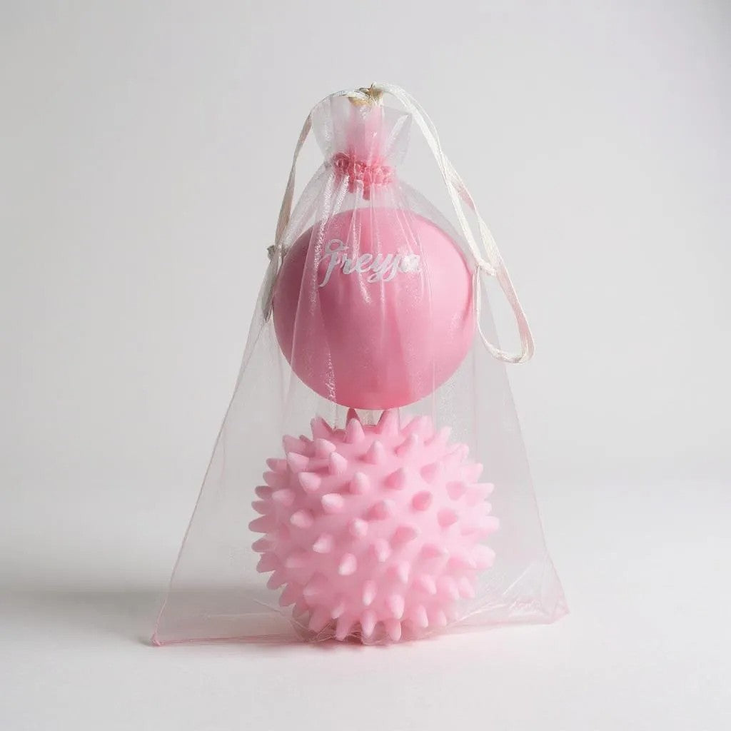 Freyja Fit pink massage ball set in a clear drawstring bag, displayed on a light grey background