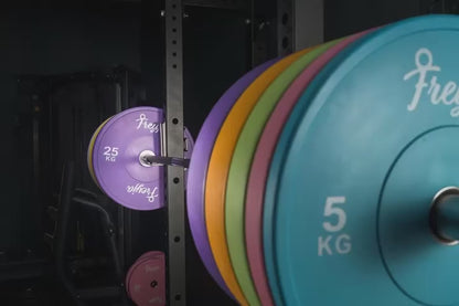 150kg set of pastel Freyja Fit bumper plates on a black squat rack in a gym