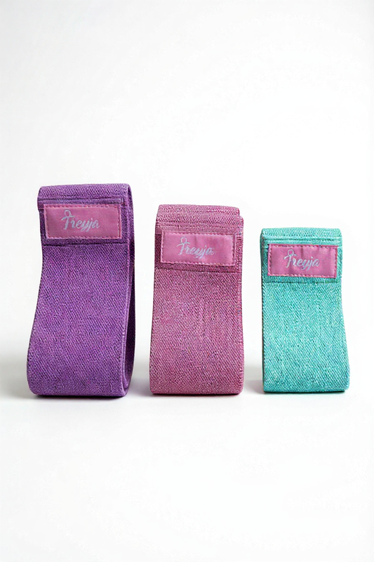 Three fabric resistance bands in purple, pink, and teal for postpartum recovery and wellness exercises.