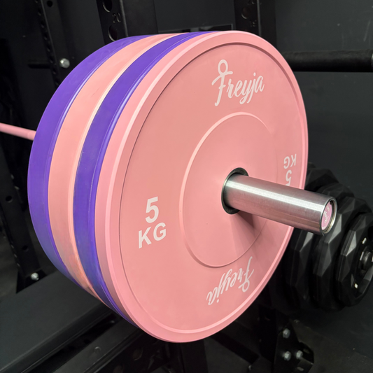 Pink weight plates and purple bumper plates on a barbell, branded 'Freyja'.