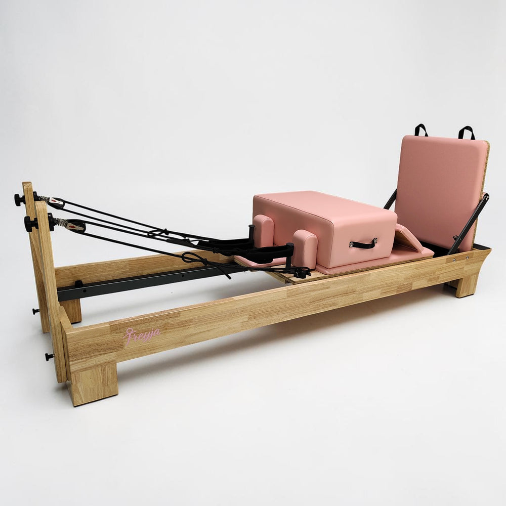 Pilates reformer with wooden frame and pink cushion