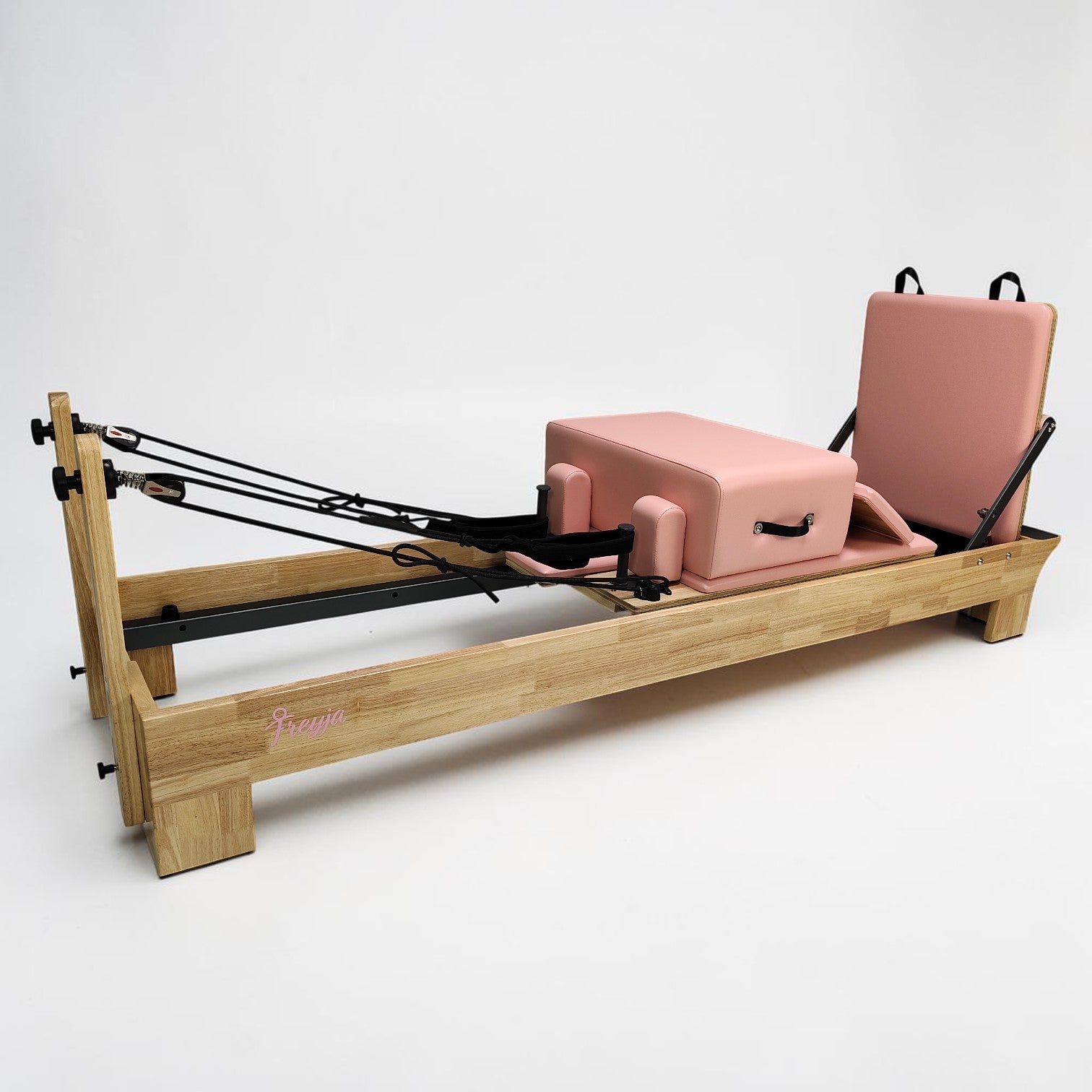 Pilates reformer with wooden frame and pink cushion