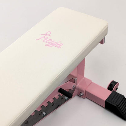 Pink and white adjustable weight bench with 'Freyja' branding on a light gray background